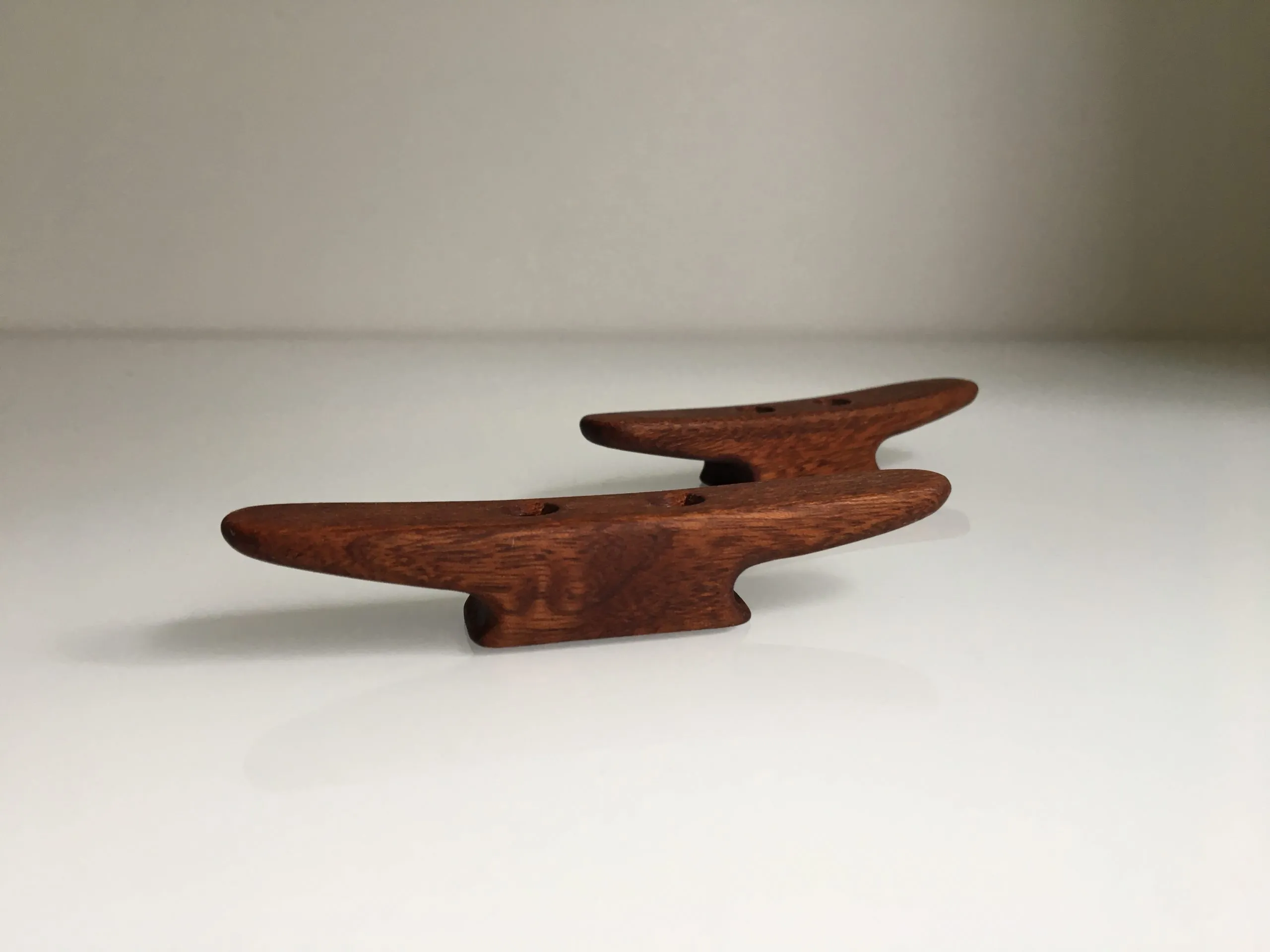 Small mahogany cleat screwed to a varnished wooden panel with stainless screws