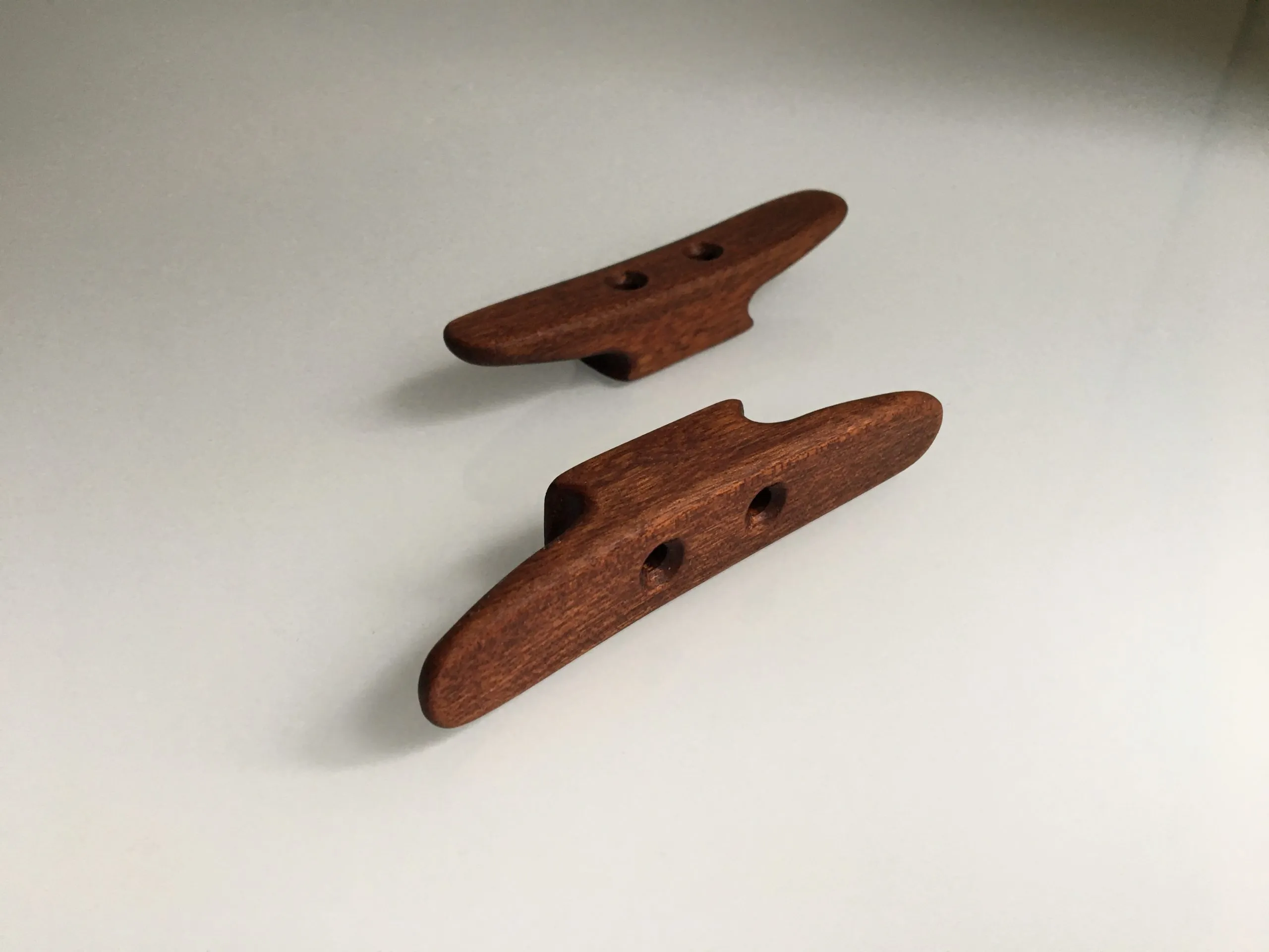 Top-down view of the mahogany cleat on a plain pale background, satin oiled finish