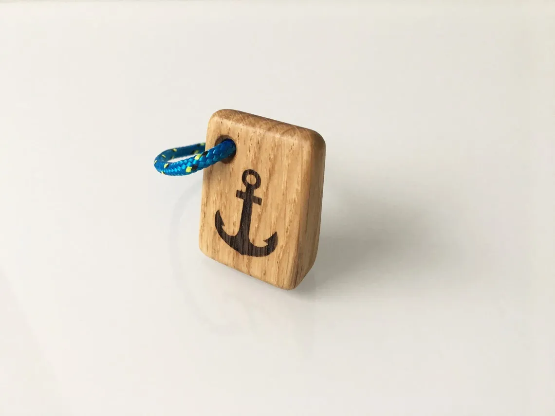 Oak keyring with a burned anchor mark lying on a weathered workbench