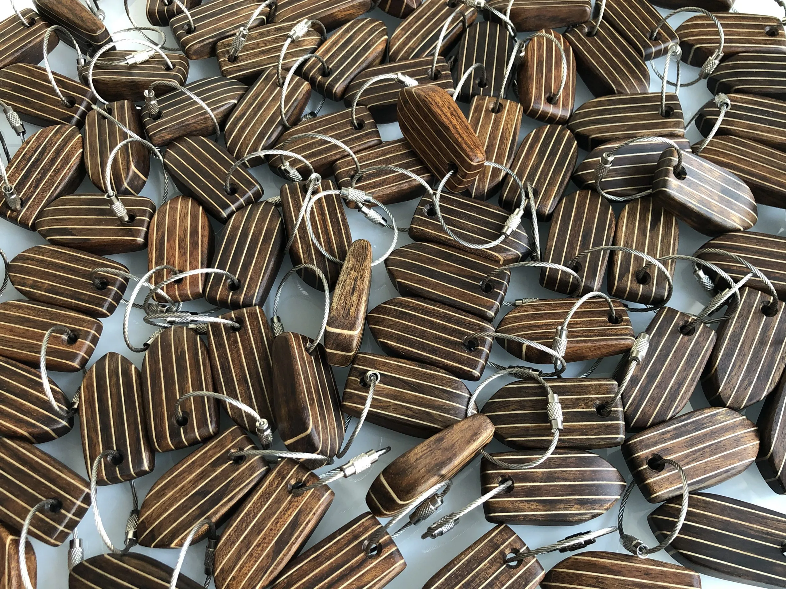 Dozens of teak deck-pattern keychains laid out together after a large order