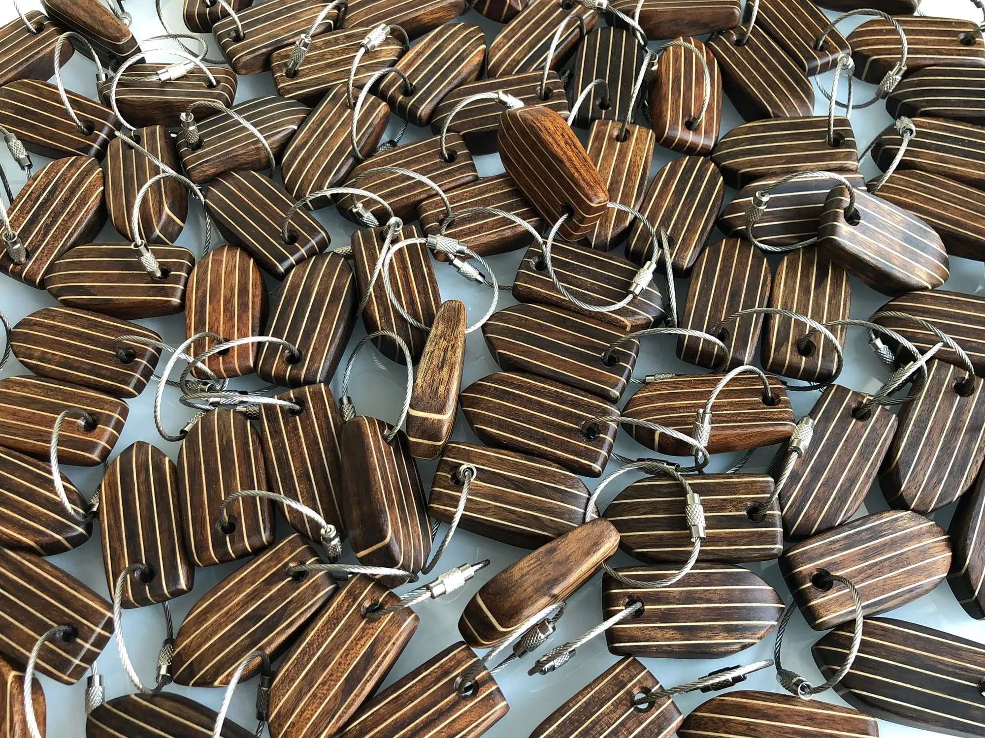 A pile of finished teak keychains on stainless rings, ready to ship