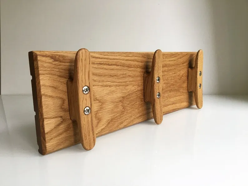 Oak coat rack with three boat cleats mounted on a white wall