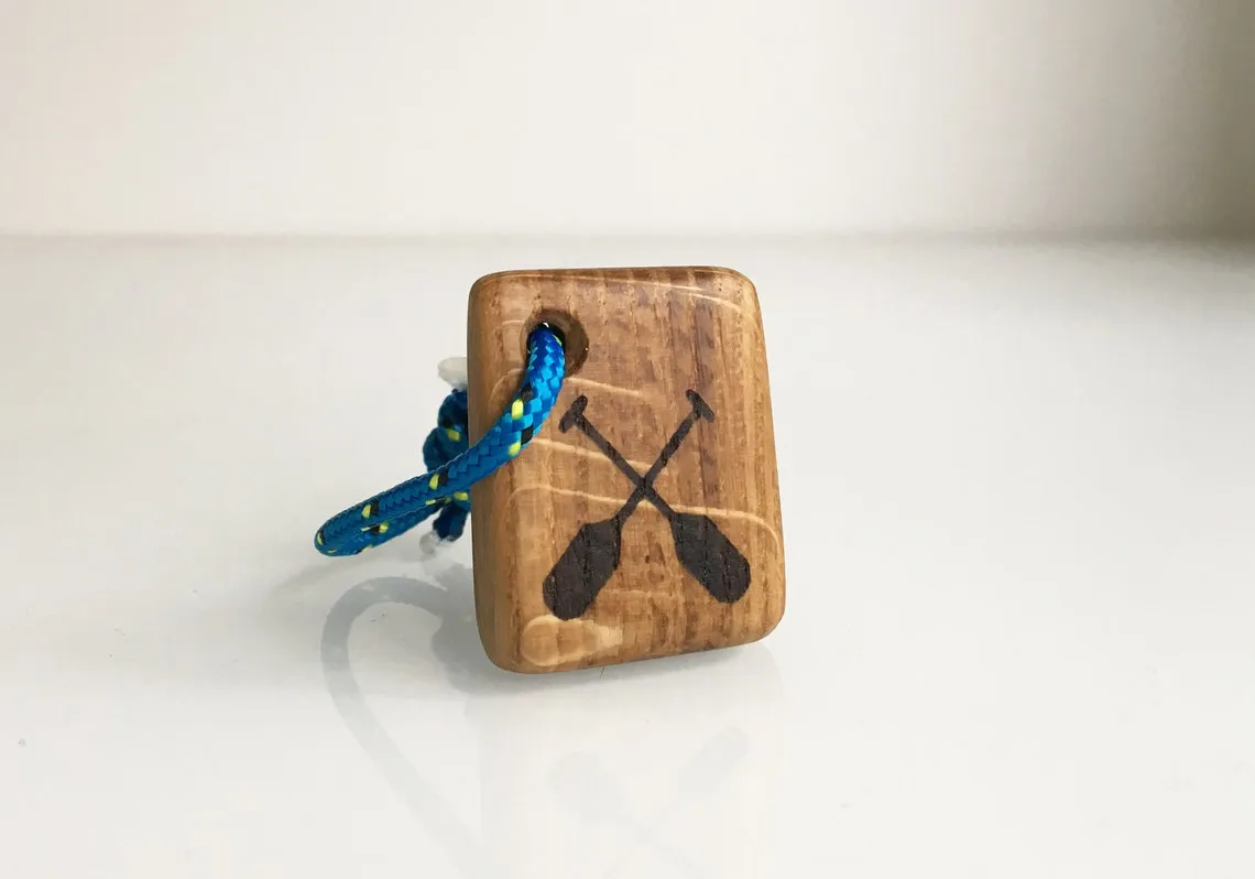 Oak keychain burned with crossed canoe paddles, lying on rough sawn timber