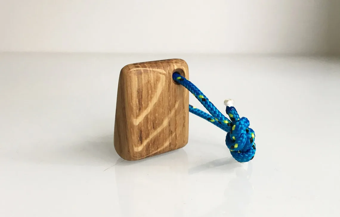 Paddle keychain held between two fingers to show its 37mm size