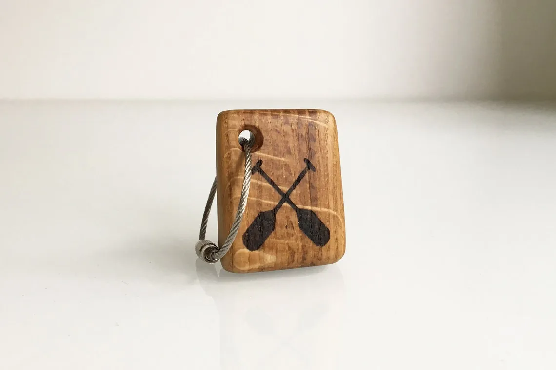 Green rope canoe keychain resting on a dark slate tile