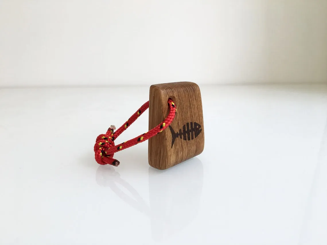 Yellow rope loop on the fish bone keychain against dark wood