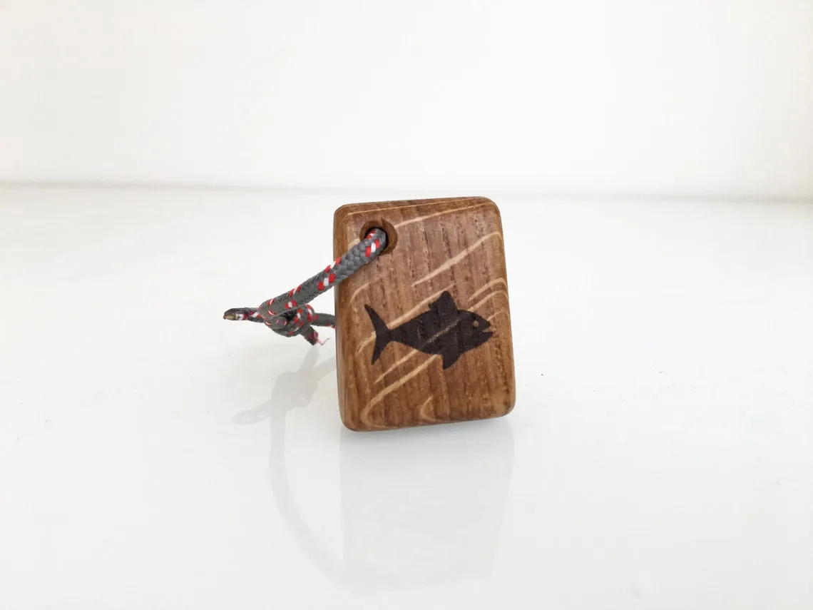 Oak keychain burned with a tuna silhouette lying on fine sawdust