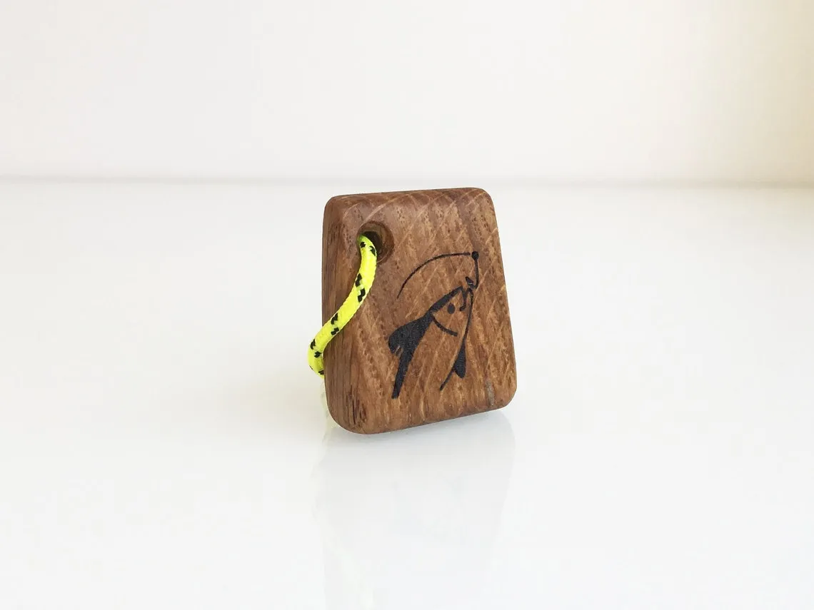 Oak keychain burned with a fish and hook motif on a workbench