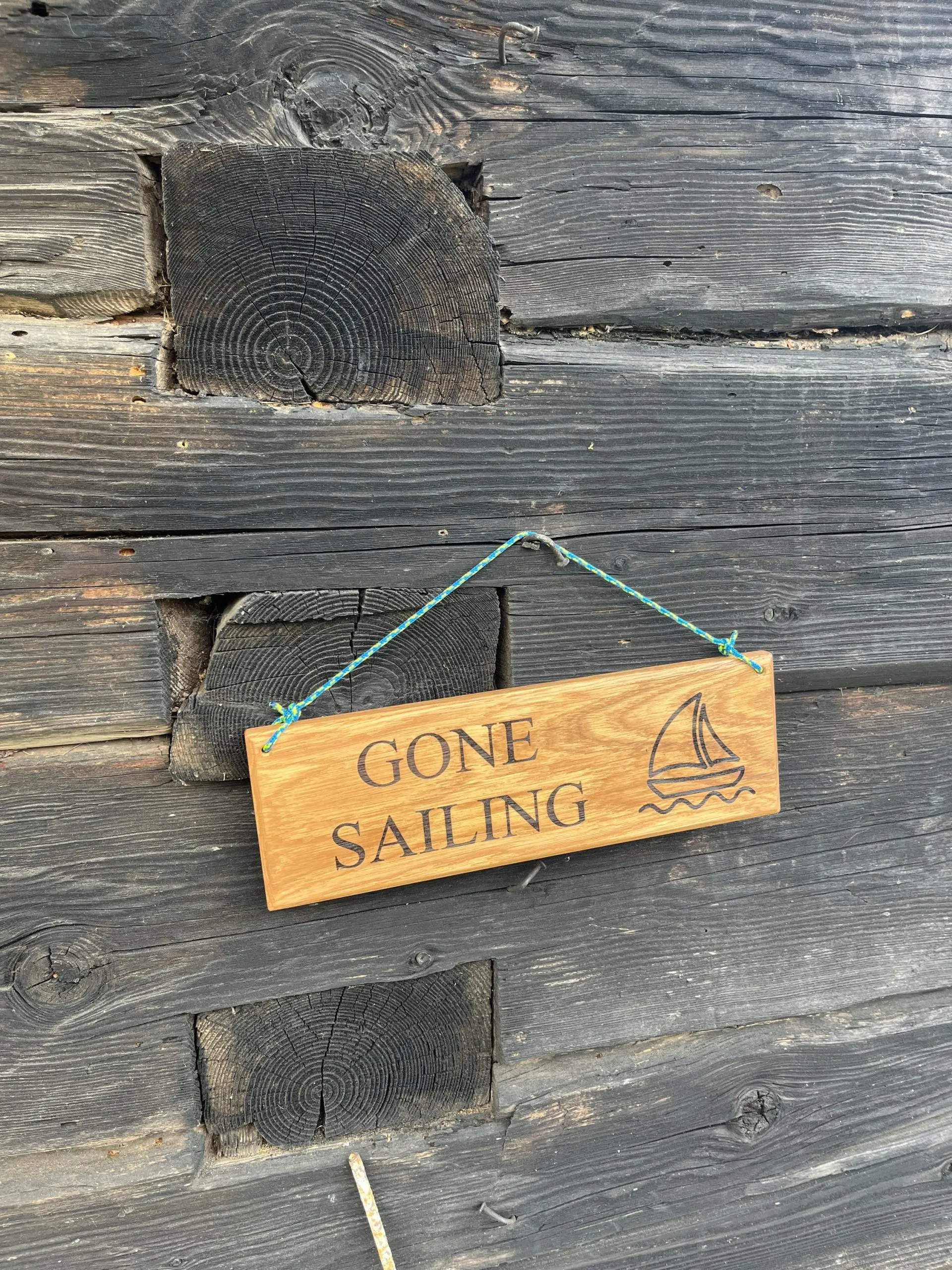 Oak sign engraved GONE SAILING hanging from a blue yacht rope