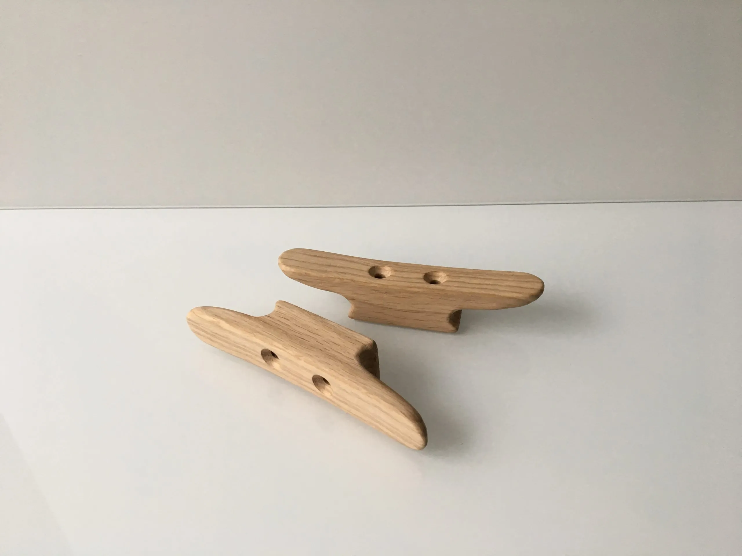 Natural finish cleat held in a hand, showing its 14cm length