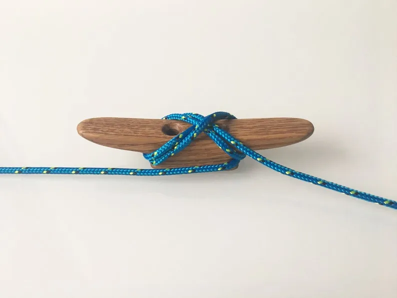 Small oiled oak boat cleat, about 10cm long, on a workbench