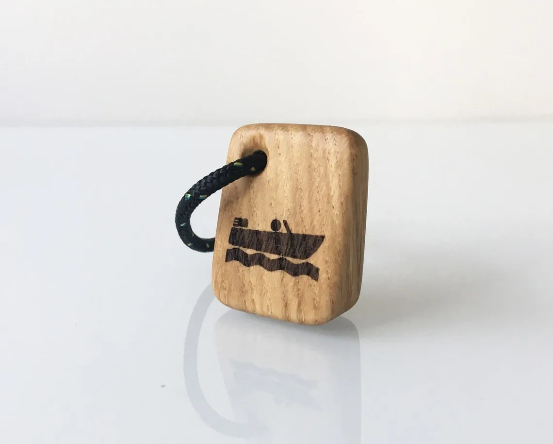 Oak keyring with a burned ship wheel emblem resting on rope