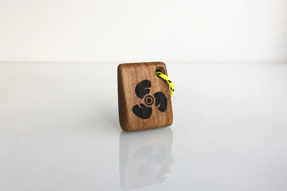 Oak keychain with a burned boat propeller mark, lying on canvas