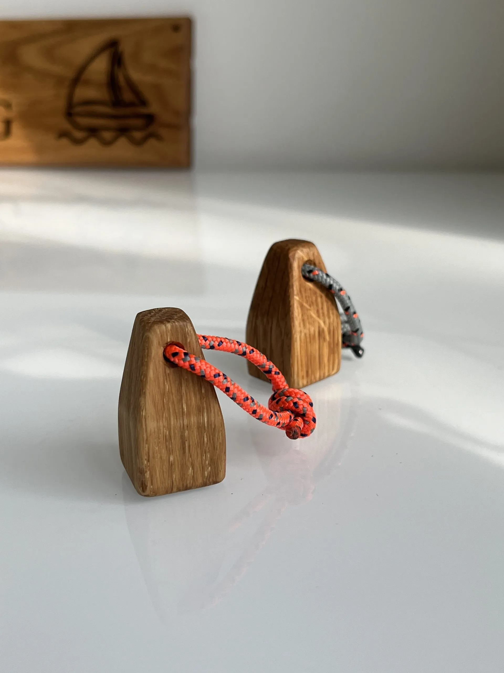 Two oak buoy-shaped fridge magnets with red and blue rope loops on a fridge door