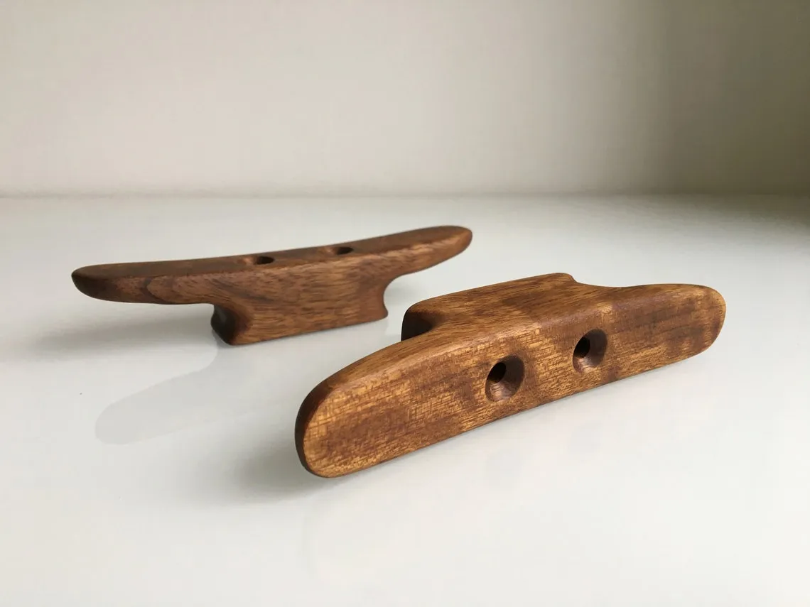 Pair of oiled teak boat cleats side by side on a workbench