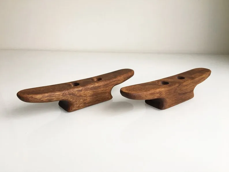 One cleat held between fingers, showing its 140 mm length