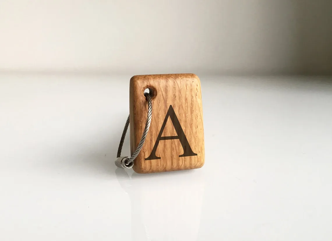 Oak keychain with a burned initial letter and a blue rope loop
