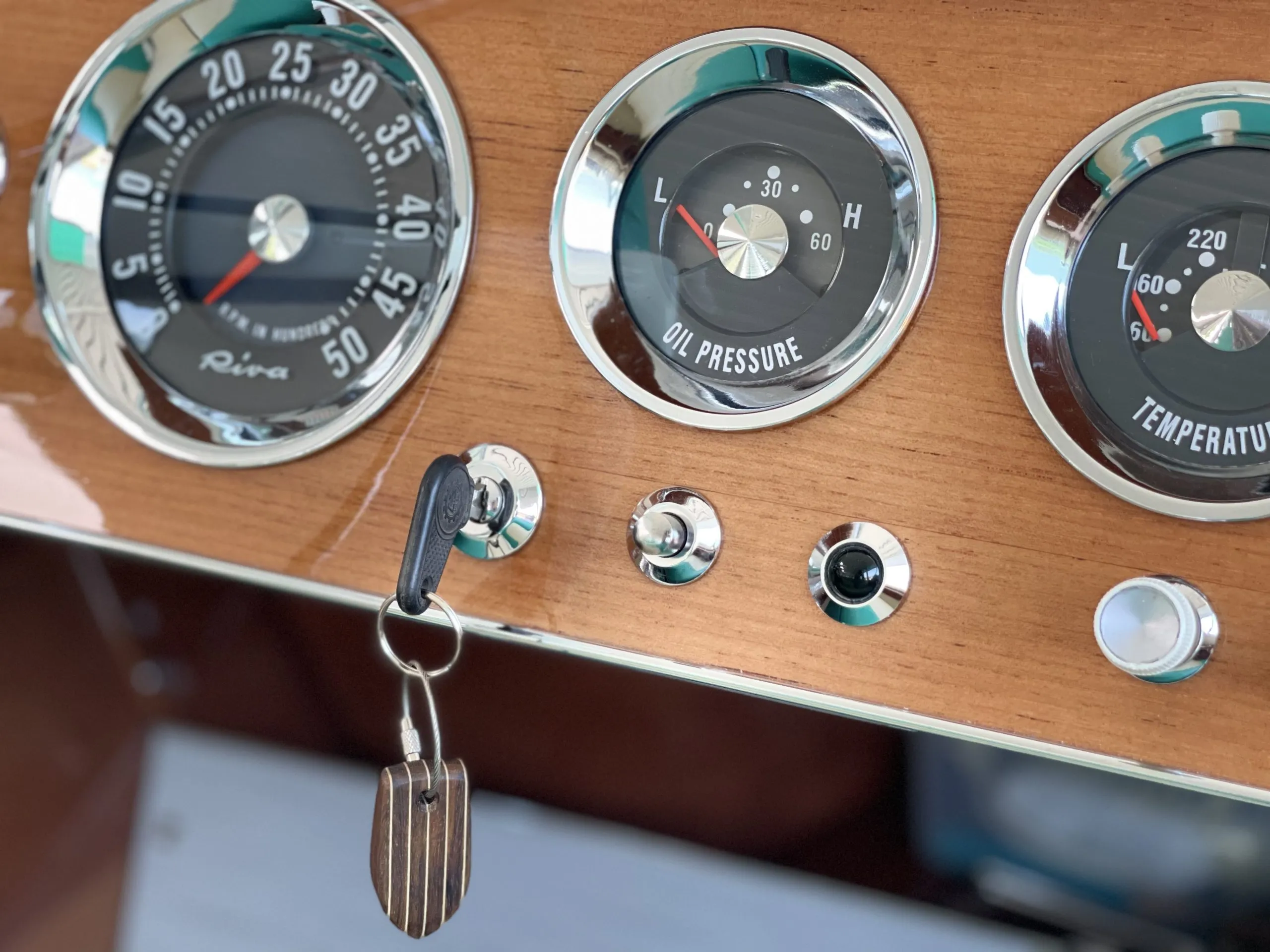 The keychain attached to a bunch of keys on a varnished boat locker