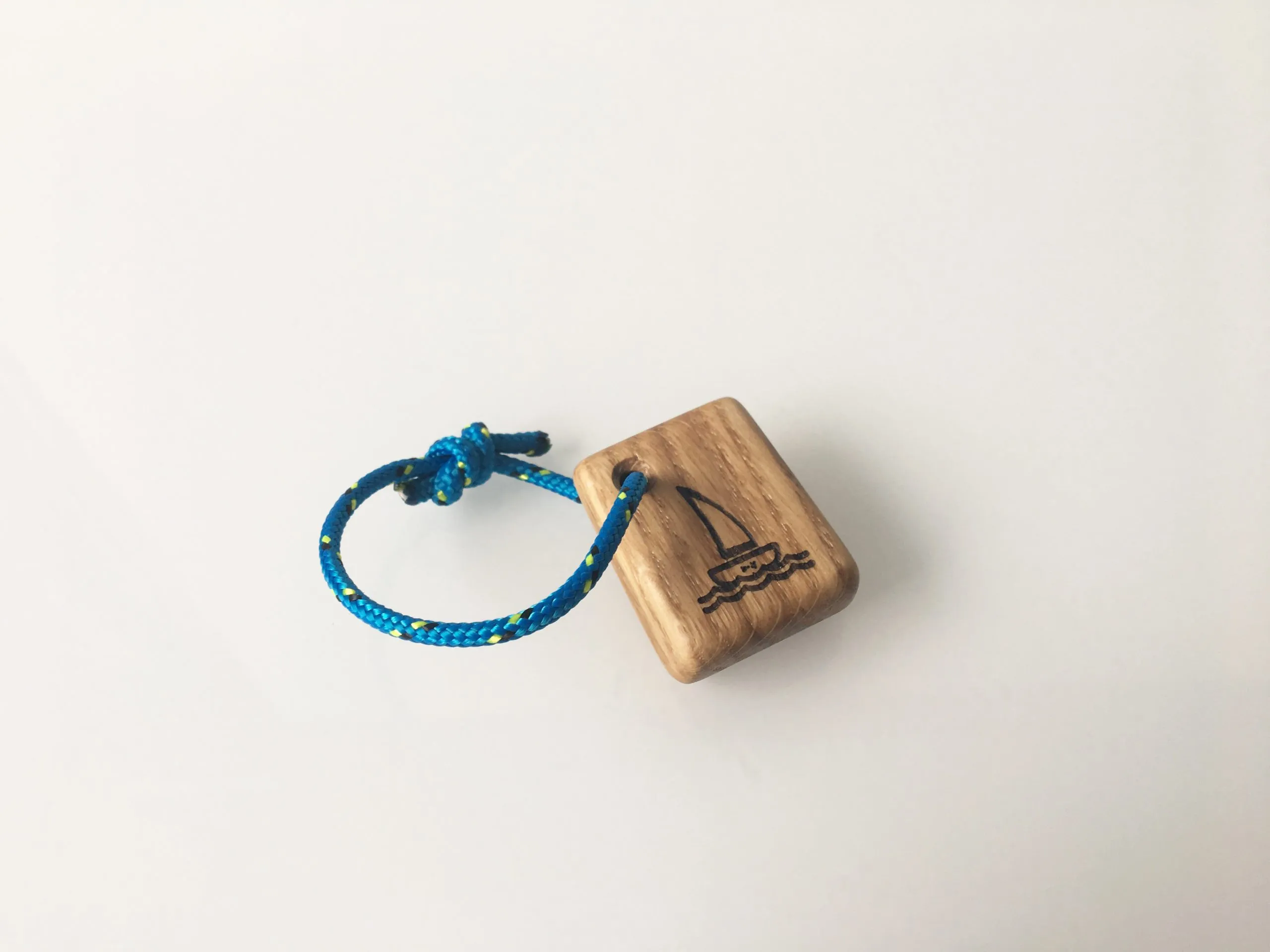 The sailing boat keychain resting on a workbench beside wood shavings
