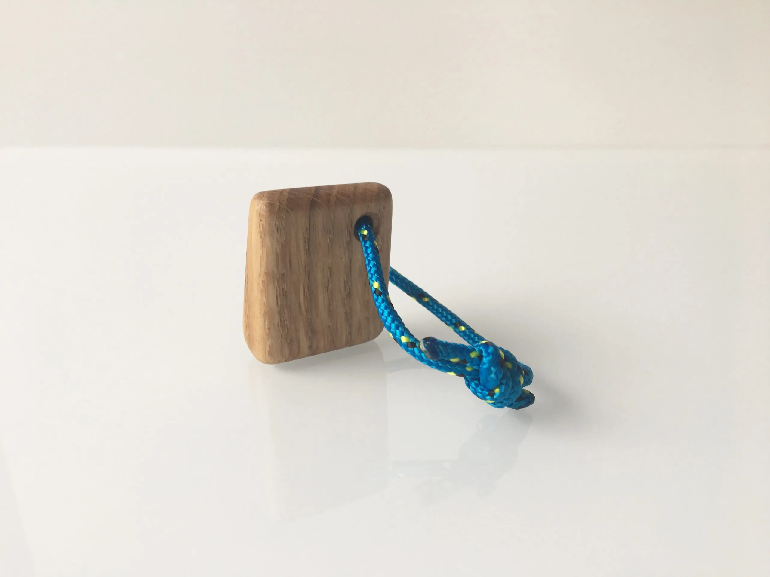 Sailboat keychain held between finger and thumb for scale