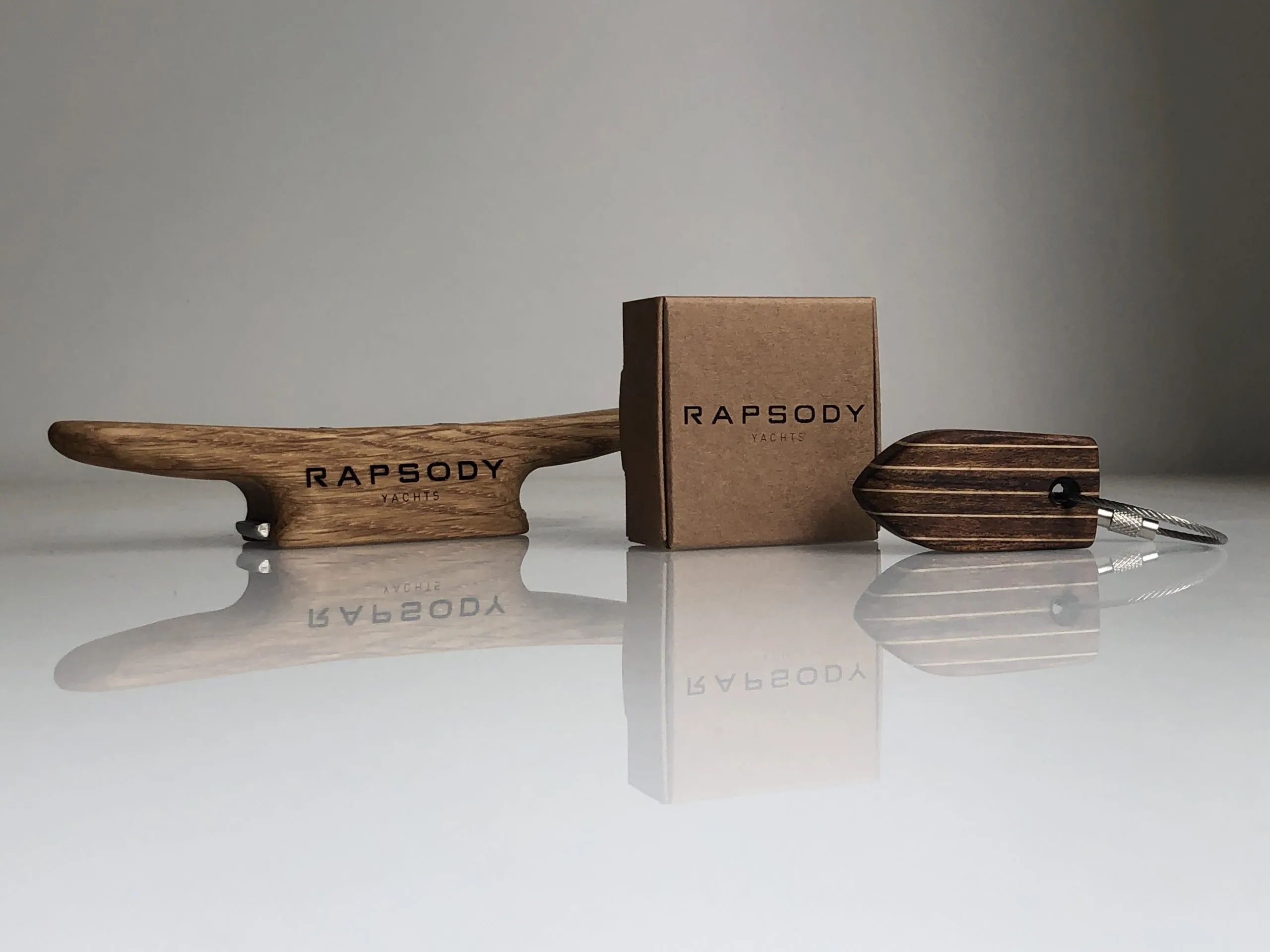 A keychain engraved RAPSODY resting beside its branded box