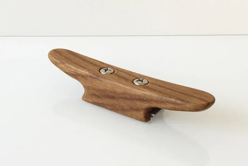 Cleat shaped opener held in a hand, ready to lift a cap