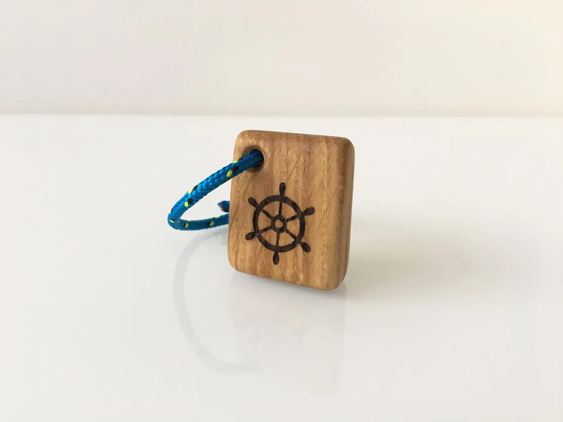 Oak keyring with a burned ship's wheel emblem and a red rope loop